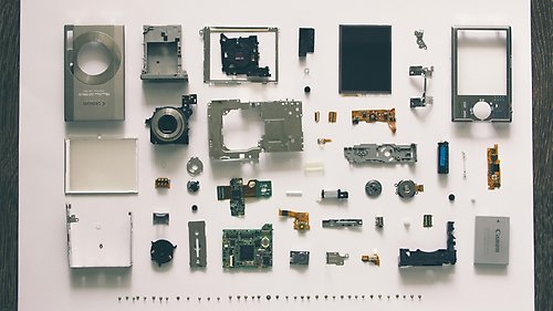 En isärplockad kamera vars delar är prydligt utspridda på en vit yta